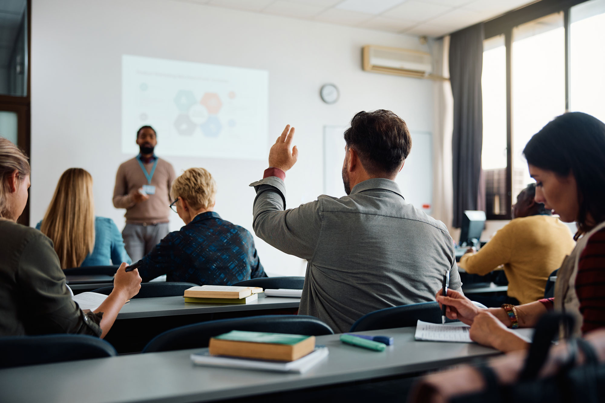 Student raising hand in a classroom lecture